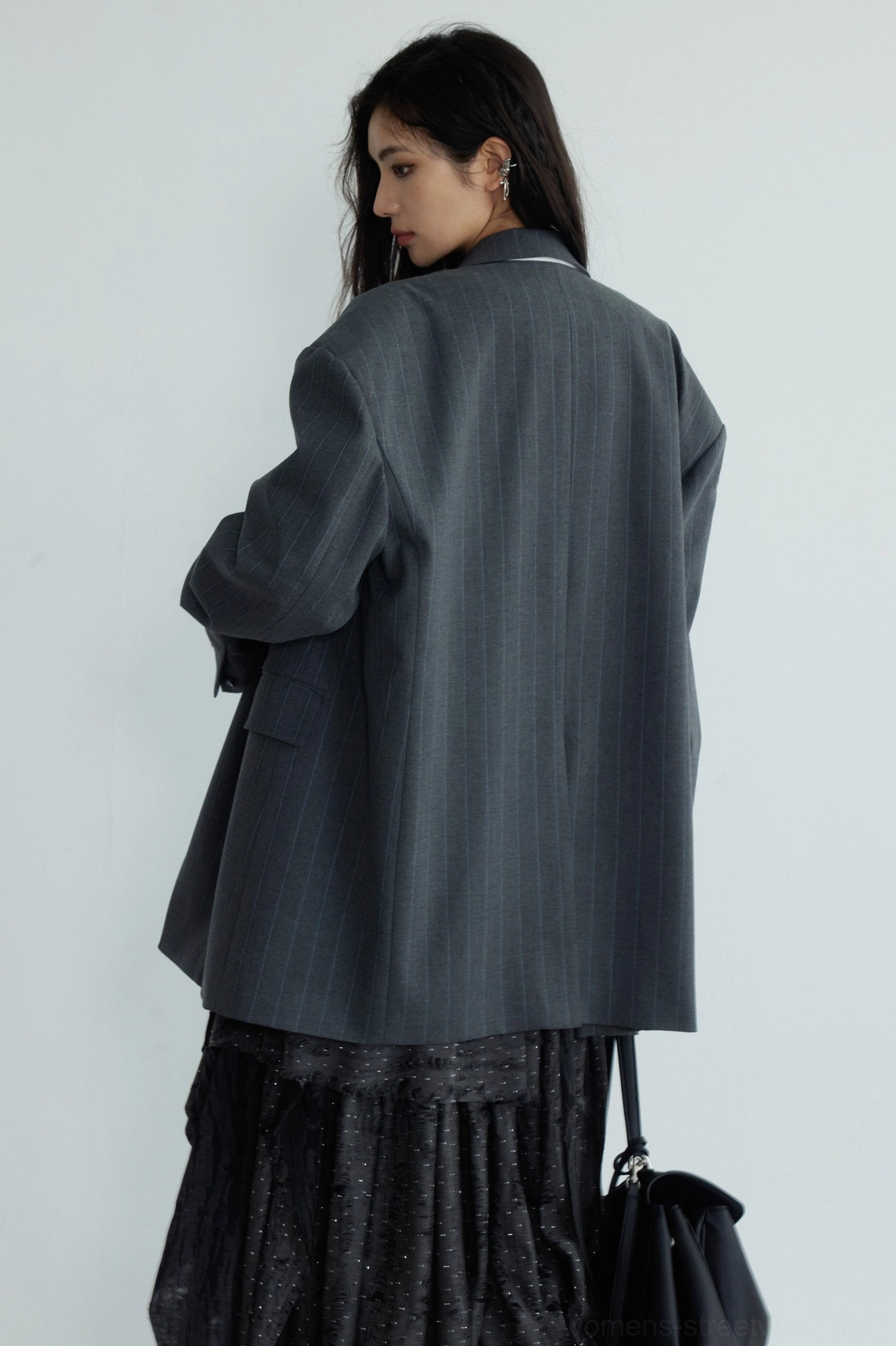 Back view of a dark gray loose striped blazer showing the relaxed drape long silhouette and fine stripe texture