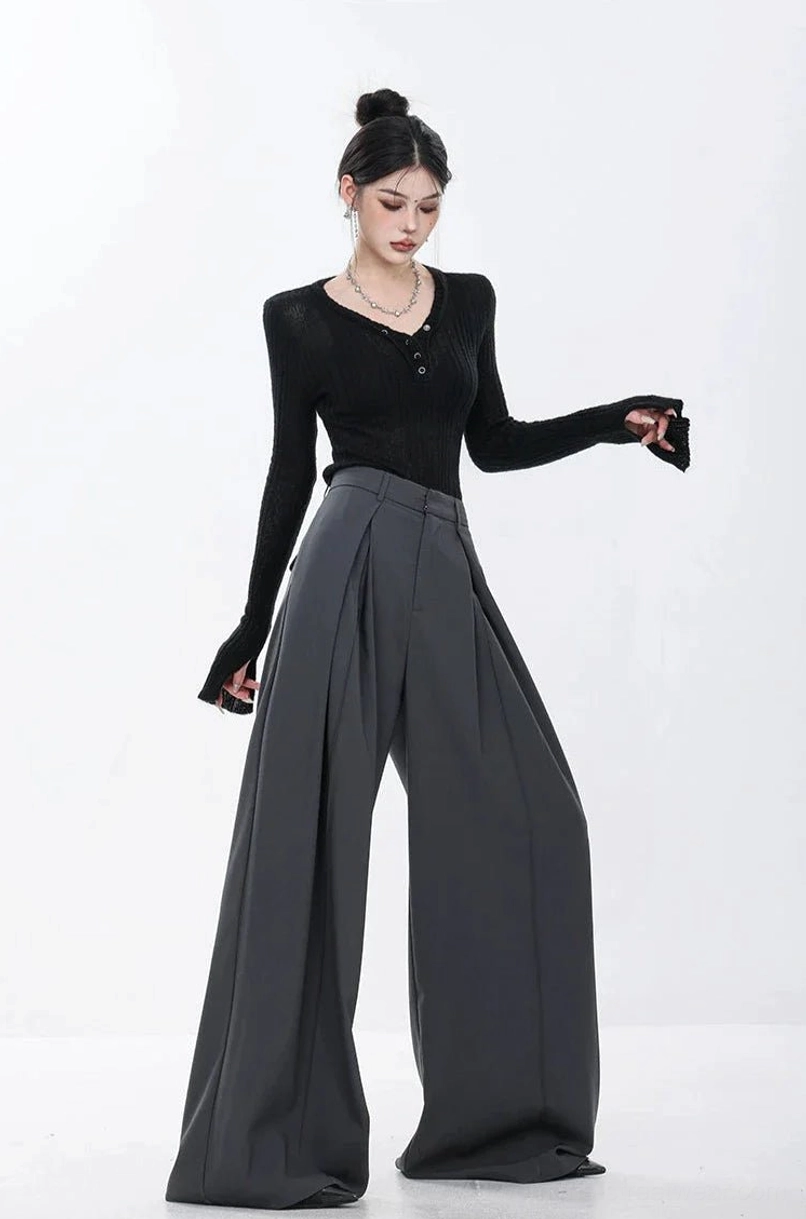 Side profile of dark gray tailored pleated trousers showing the relaxed extra-wide leg silhouette