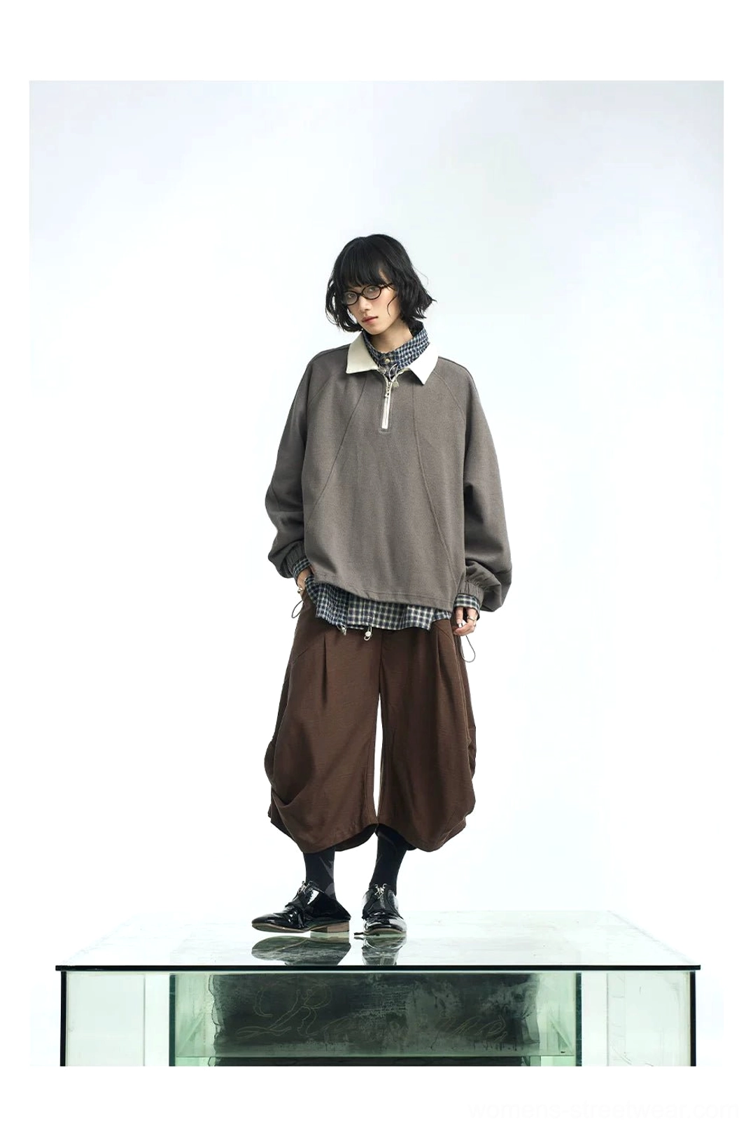 Dark gray taupe half-zip polo pullover layered over a checked shirt with cropped brown trousers