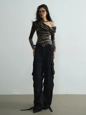 Women's dark gray asymmetrical velvet off-shoulder top styled with high-waisted wide-leg cargo pants, leather belt, and modern Korean streetwear accessories