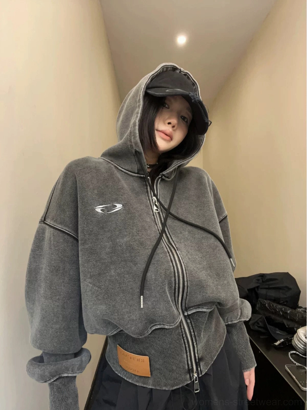Close-up front view of a dark gray washed cropped zip hoodie with relaxed oversized sleeves, exposed metal zipper, and Korean streetwear silhouette
