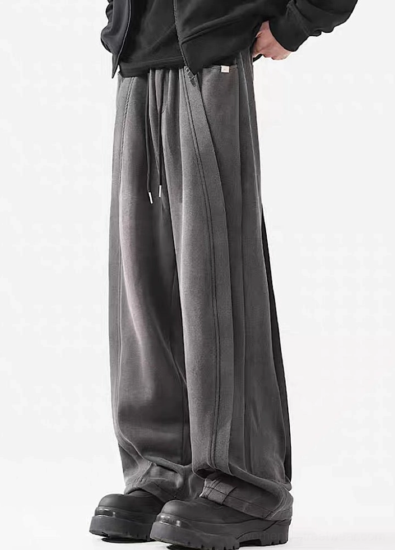 Rear side view of dark gray washed streetwear pants with wide stacked hems styled with chunky black work boots
