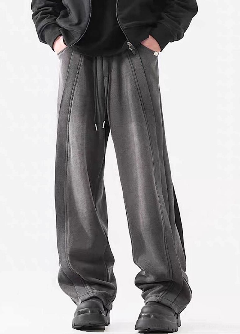 Side front view of dark gray washed wide-leg pants featuring relaxed streetwear tailoring and structured vertical seams