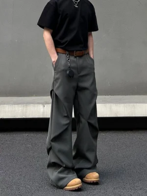 Dark gray wide-leg streetwear trousers with vertical draped pleats and metal chain pendant styled in a modern Seoul fashion outfit