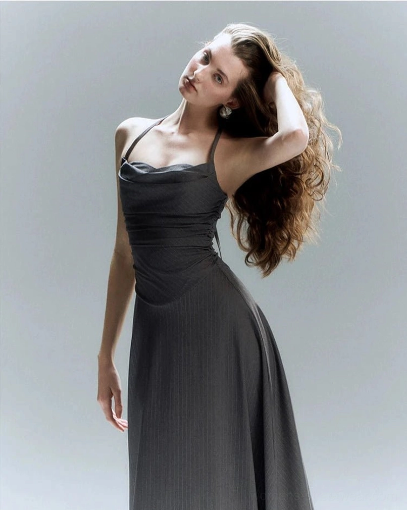 Dark grey halter cowl neck floor length formal dress with ruched torso and flowing A line skirt shown from the side