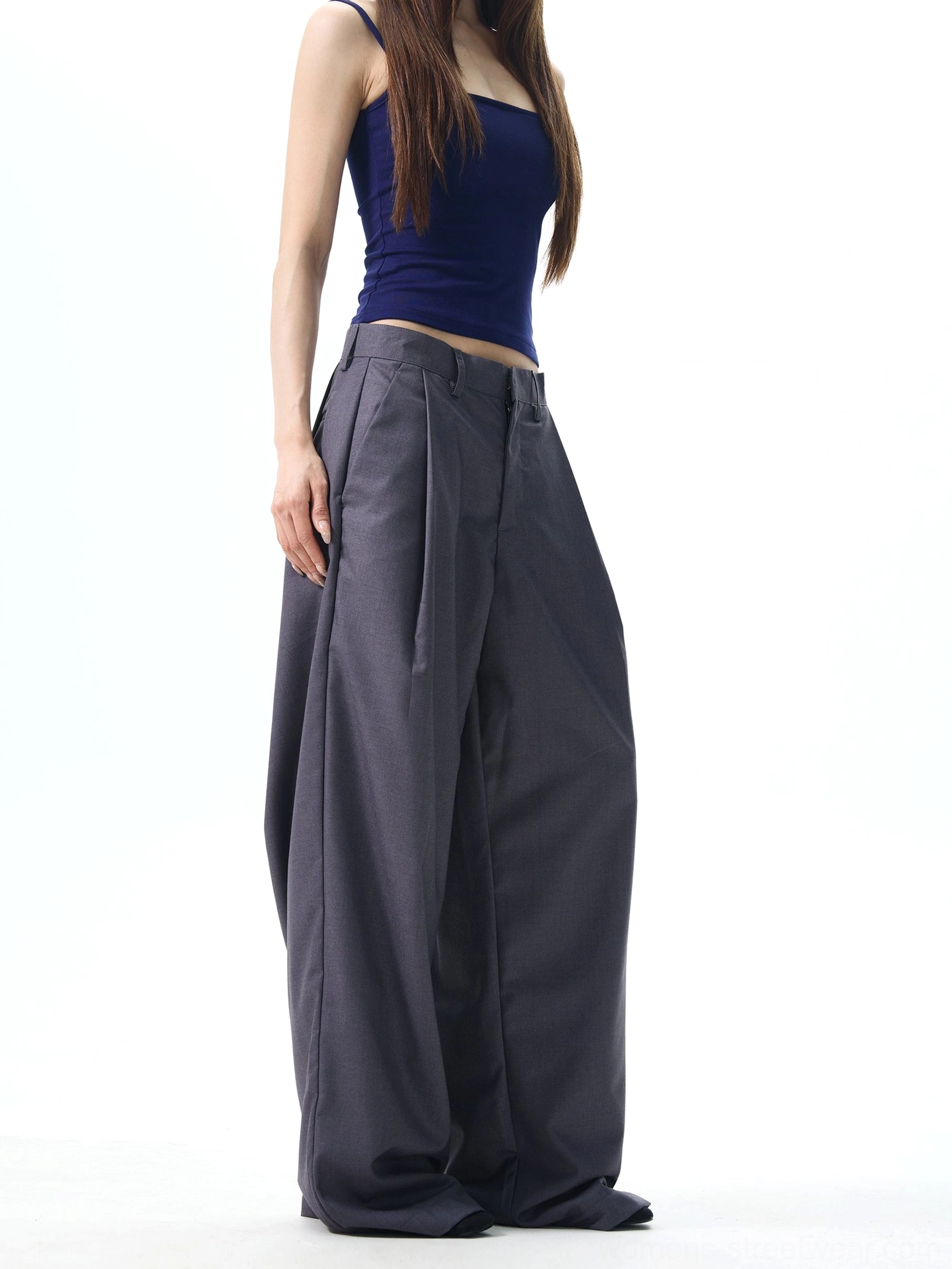 Dark grey high-rise pleated wide-leg streetwear trousers shown from the side with fluid draping and a relaxed tailored fit