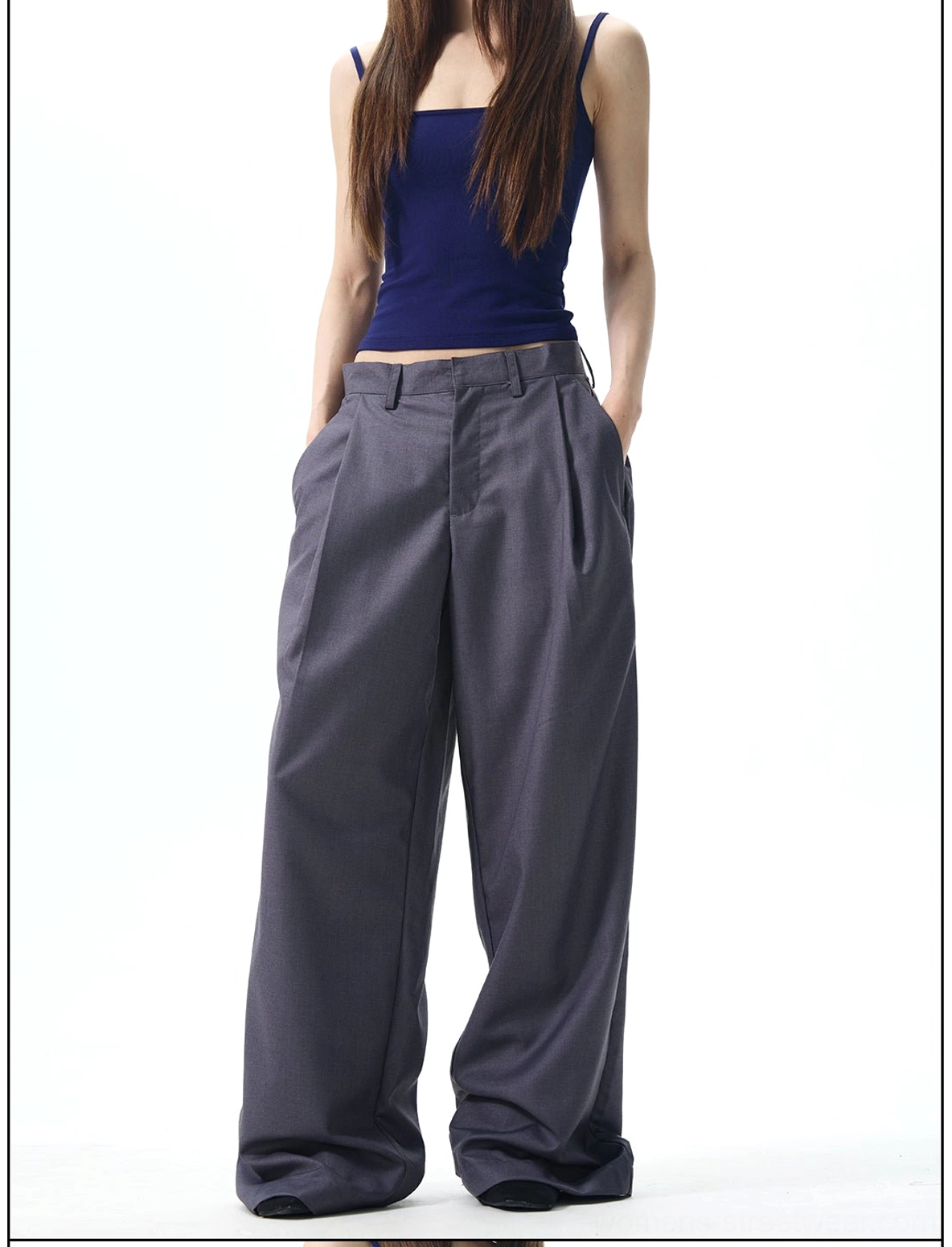 Female model wearing dark grey high-waisted pleated wide-leg streetwear pants with floor-length legs and visible side pockets