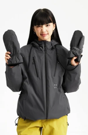 Dark grey outdoor padded hooded jacket worn with yellow outdoor pants, front zipper, chest pockets, and matching mittens