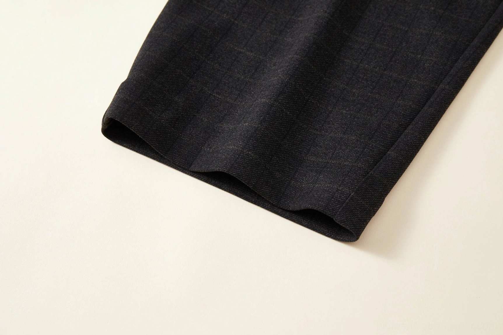Close-up of the neatly tailored wide hem on dark grey plaid high-waisted palazzo pants