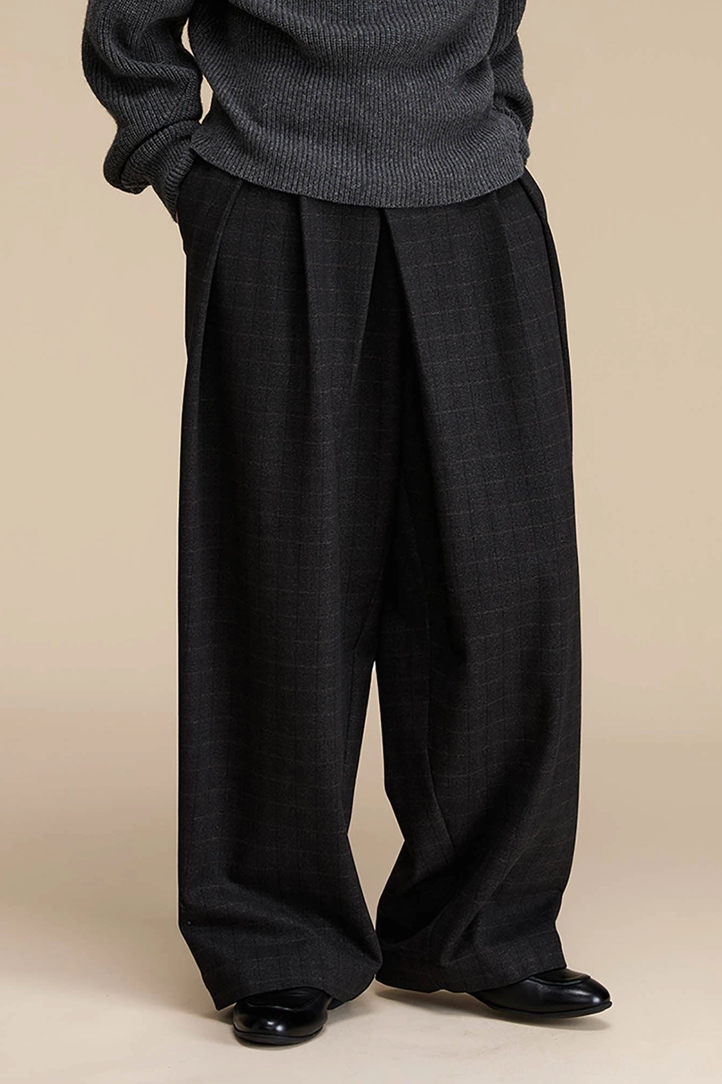 Back view detail of dark grey plaid high-waisted wide-leg pants with a loose fit, side pockets, and tailored drape