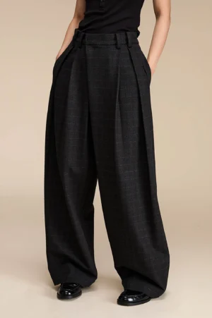 Dark grey plaid high-waisted wide-leg streetwear palazzo pants styled with a black top and leather shoes in a full front view