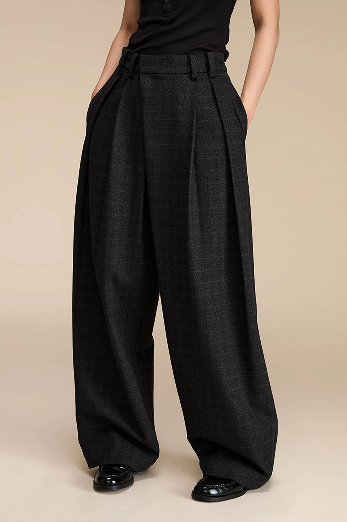 Dark grey plaid high-waisted wide-leg streetwear palazzo pants styled with a black top and leather shoes in a full front view