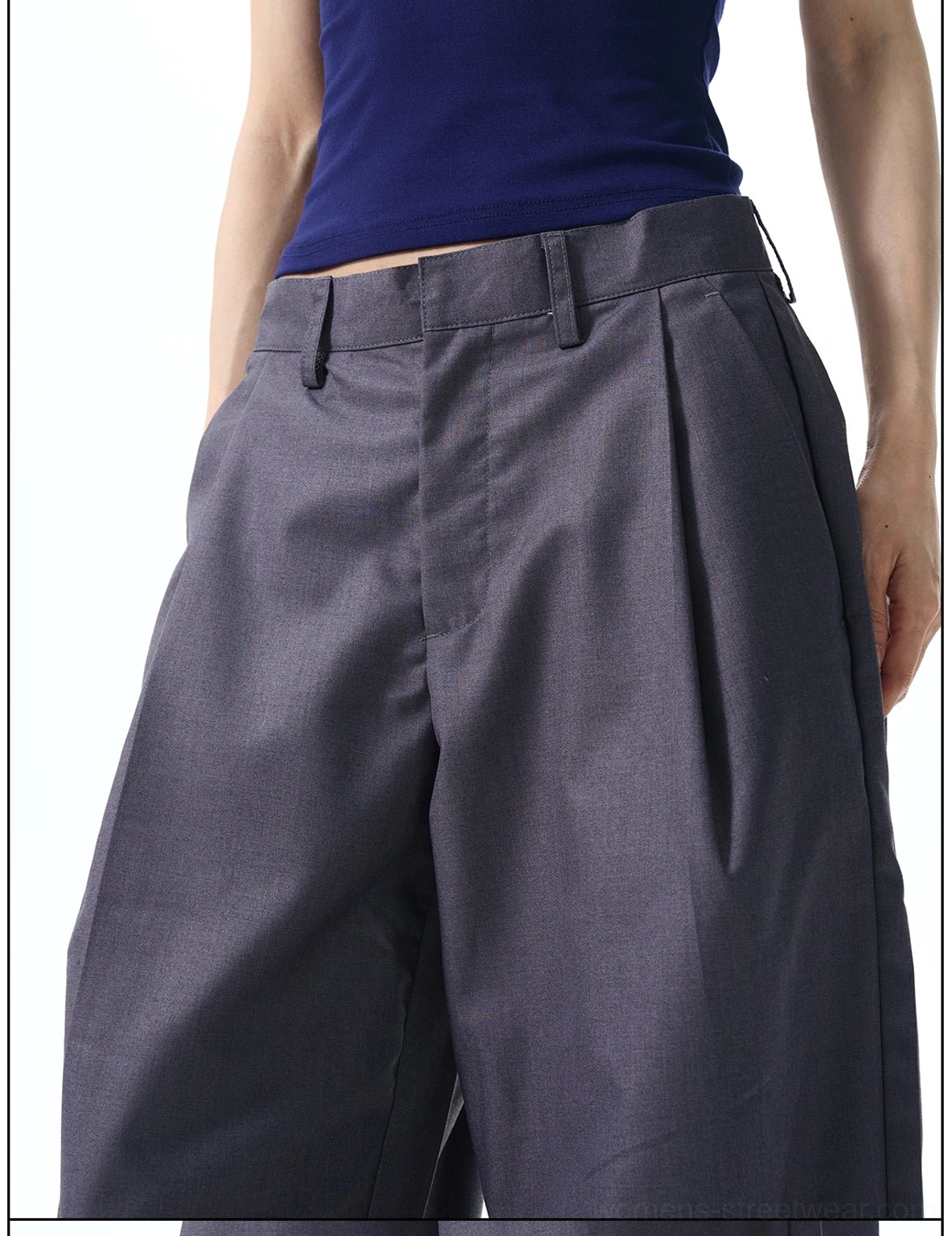 Close-up of dark grey pleated dress pants waistband with belt loops, button closure, and smooth suiting-style fabric texture