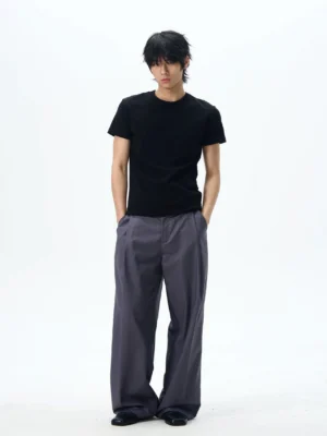 Dark grey pleated wide-leg dress pants shown on a male model in a relaxed Korean streetwear outfit with side pockets