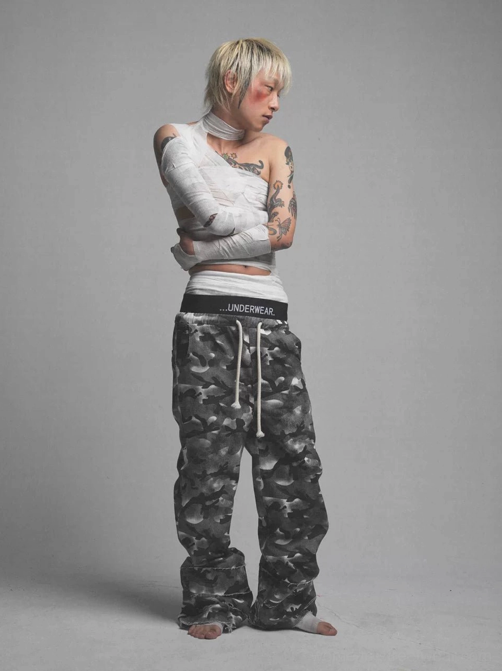 Side profile of dark grey smoke camo wide leg pants with relaxed baggy fit, drawstring waist, and stacked streetwear silhouette