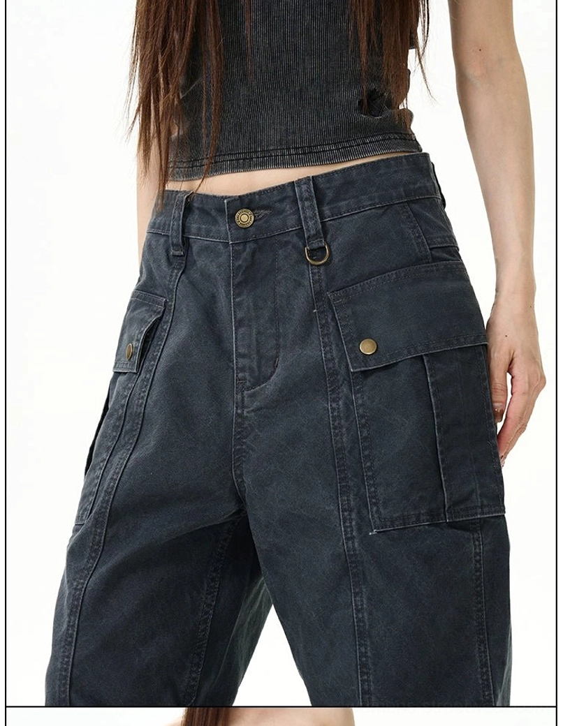 Close-up of dark grey vintage cargo pants showing metal button closure, belt loops, snap flap pockets, and washed fabric texture