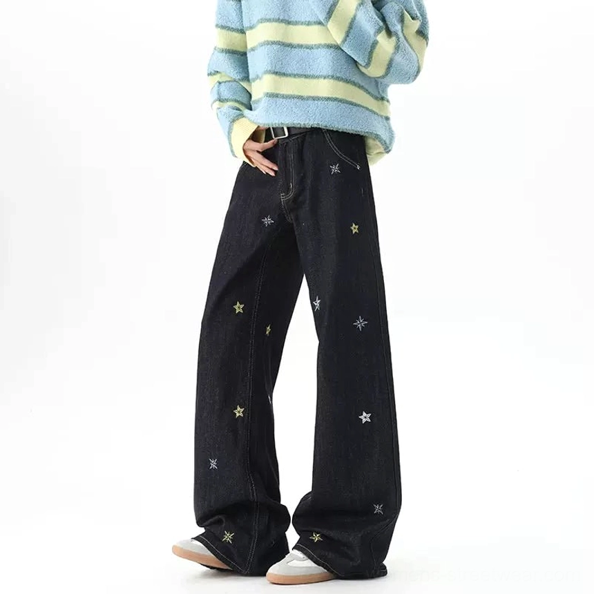 Side view of dark indigo embroidered wide-leg jeans showing loose drape, folded hem, and casual streetwear fit