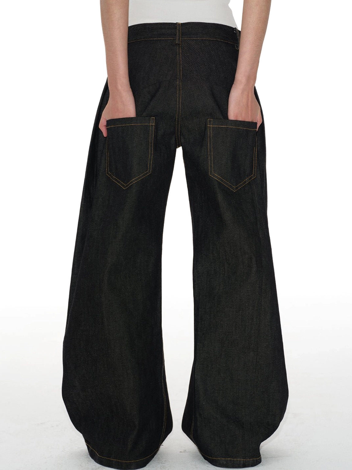 Back cropped model view of dark indigo low-rise curved jeans with dual large patch pockets and wide banana-leg shape
