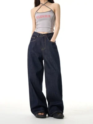 Back-side view of dark indigo wide-leg denim jeans on a female model showing the relaxed fit, waistband, pockets, and everyday streetwear silhouette