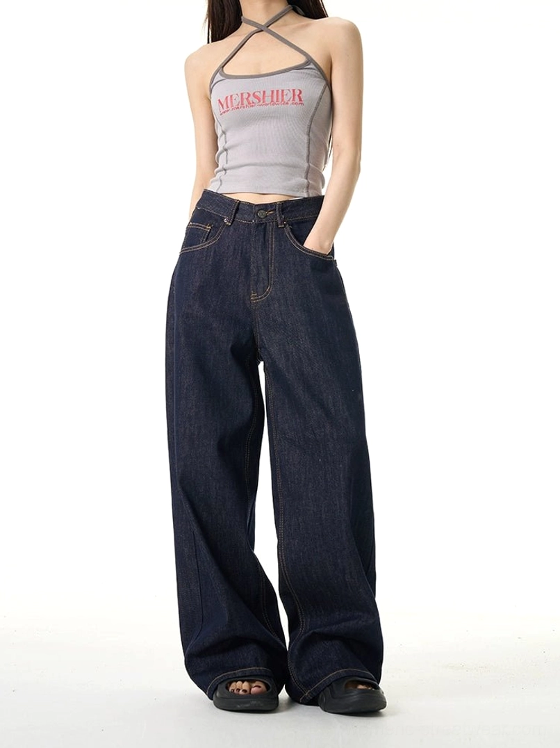 Back-side view of dark indigo wide-leg denim jeans on a female model showing the relaxed fit, waistband, pockets, and everyday streetwear silhouette