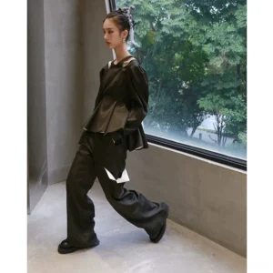 Side view of dark military green structured puff sleeve peplum top with shoulder cutouts and tailored waist silhouette