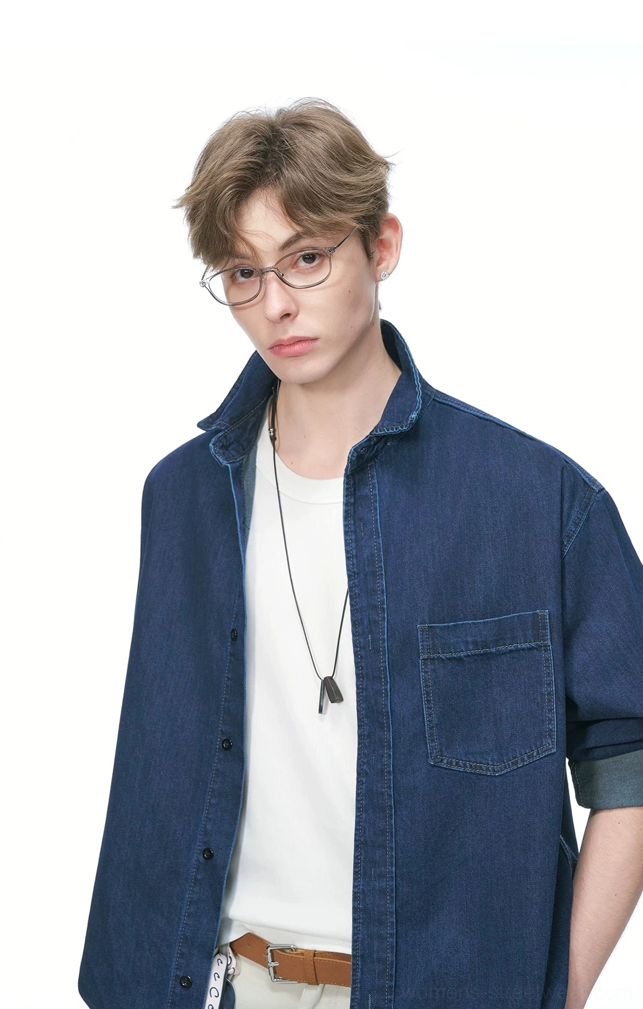Close-up front view of a dark navy oversized denim shirt with tailored collar, button placket, chest patch pocket, and rolled cuffs