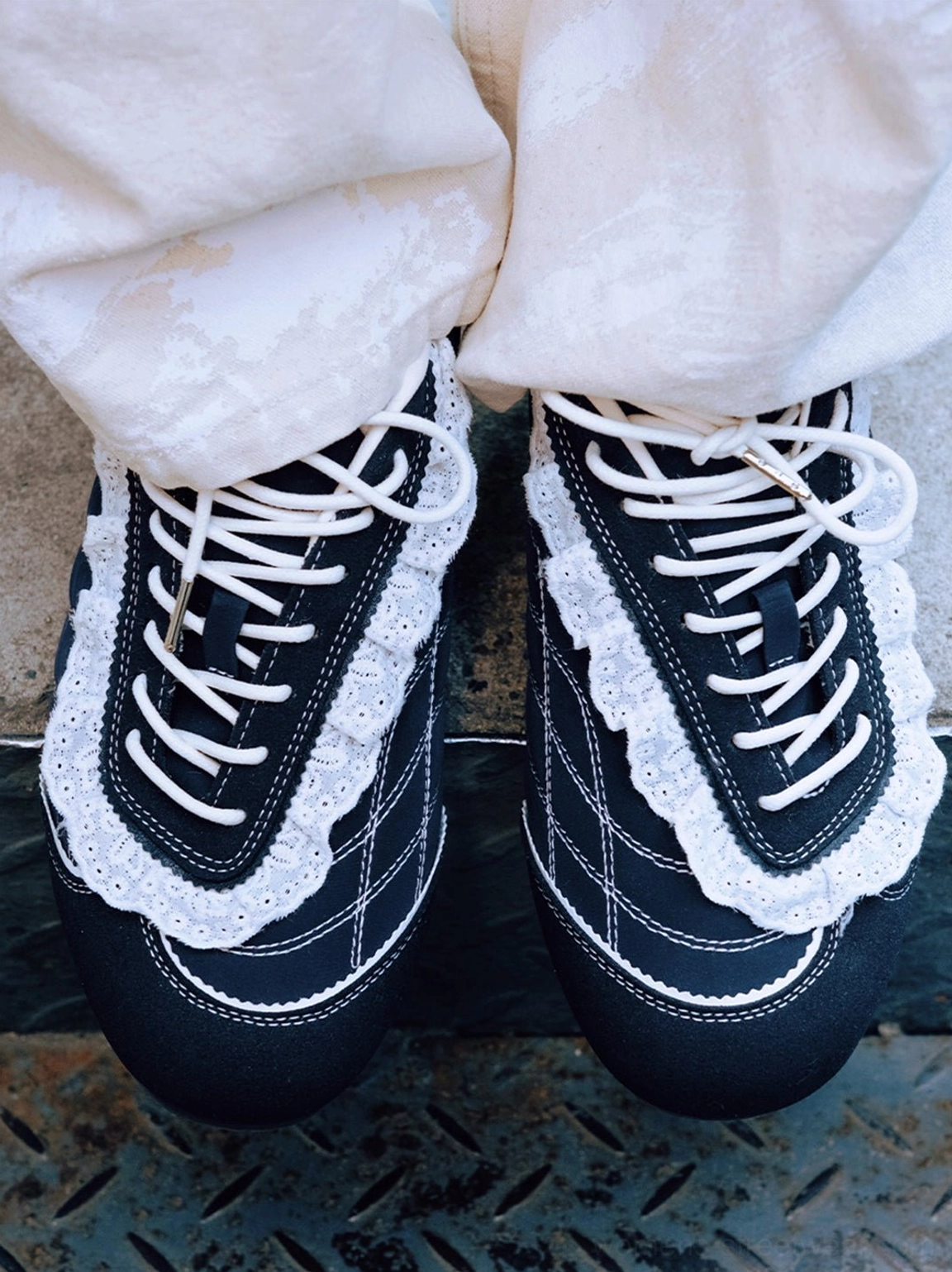 Top view of dark navy ruffled lace trainers showing white decorative lace trim and grid-style contrast stitching