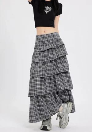 Back three quarter view of a flowing dark plaid maxi skirt with multiple ruffled tiers and full length streetwear silhouette