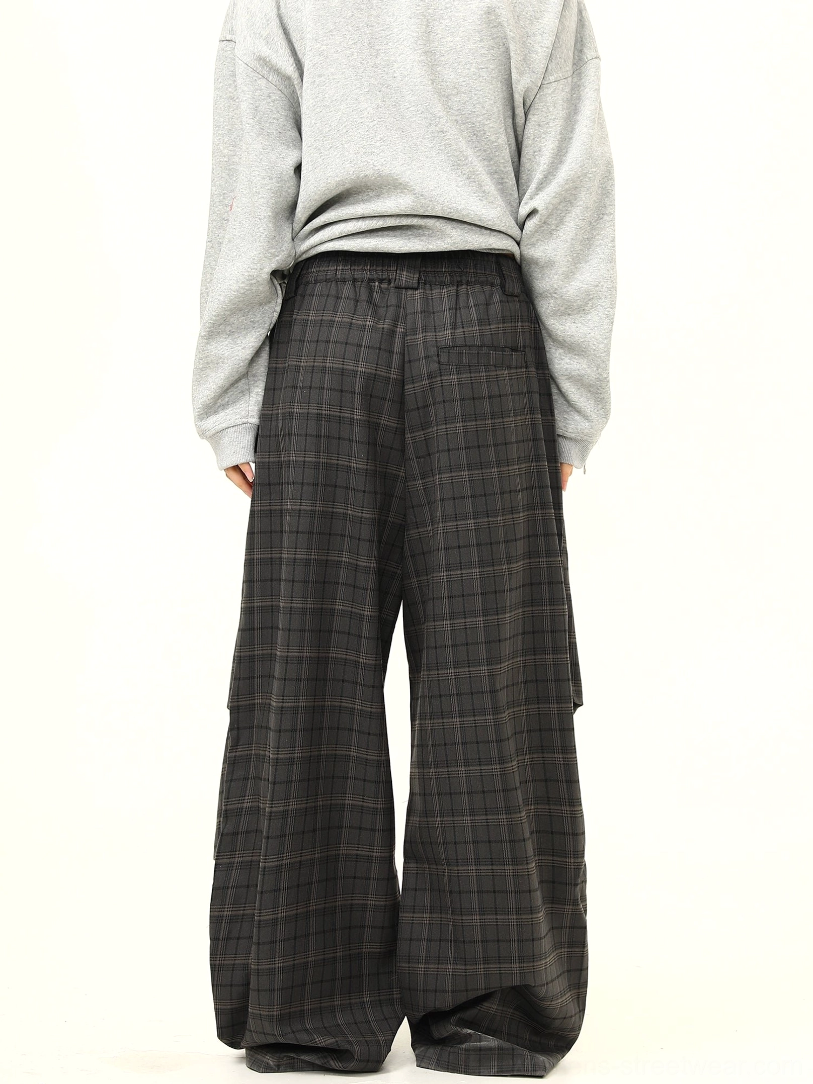 Back view of full-length dark plaid wide-leg streetwear pants with button waist closure and oversized sweatshirt