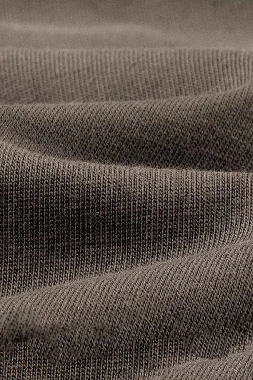 Close-up of soft heavyweight cotton jersey fabric on a dark taupe oversized streetwear T-shirt with natural texture and wrinkling