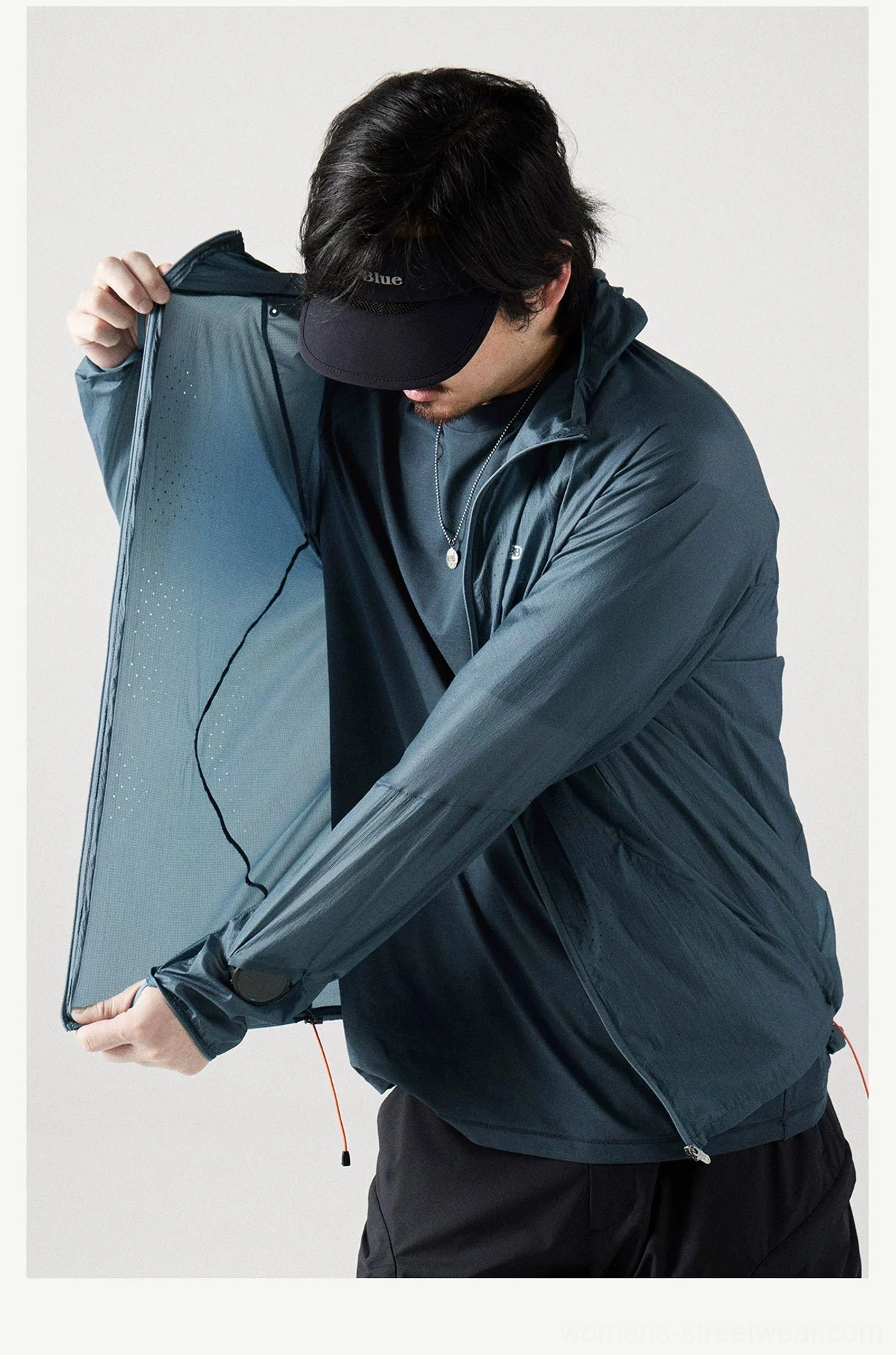 Front side close-up of the Dark Teal lightweight windbreaker showing the full zipper, adjustable hem drawstring, and crinkled fabric