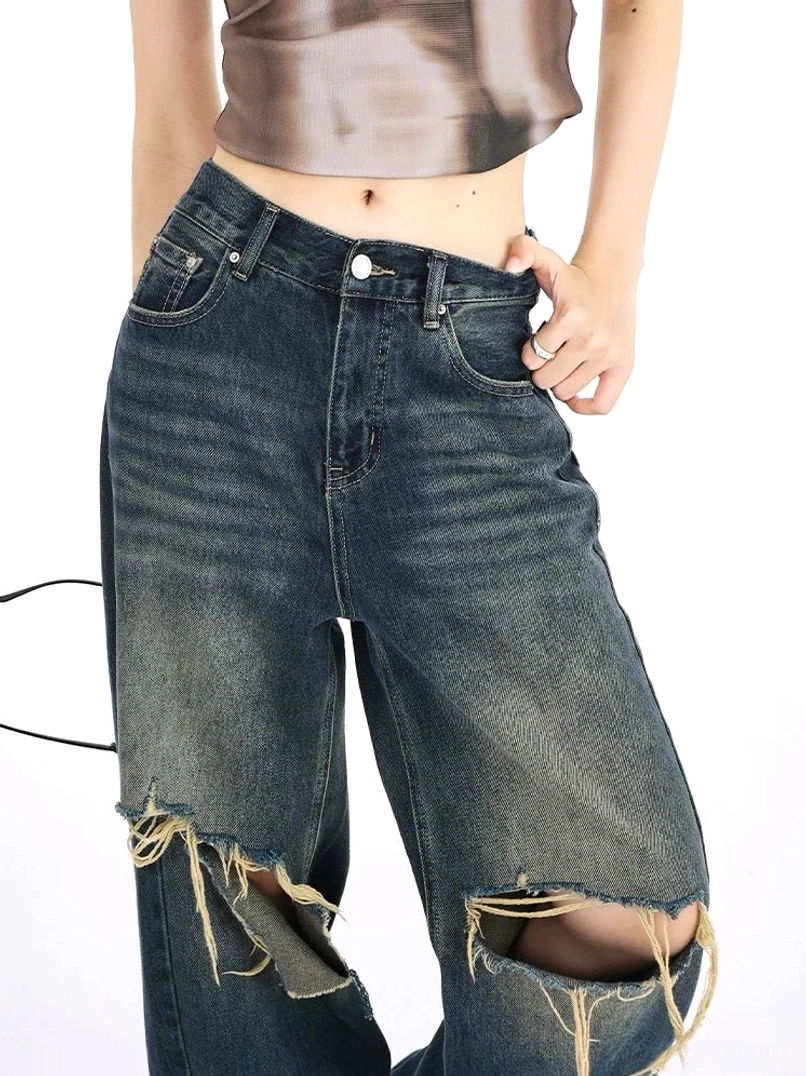 Dark vintage distressed wide leg jeans for women with a loose high-rise silhouette, raw frayed knee rips, classic denim construction, and Y2K-inspired streetwear character