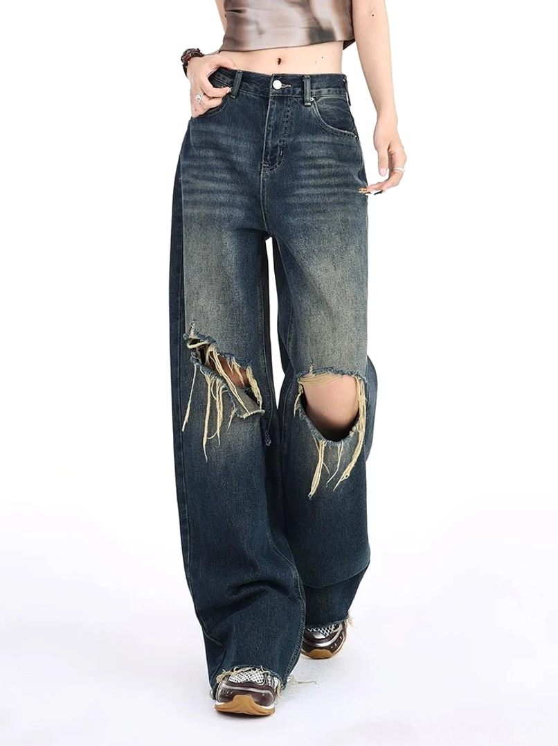 Right side view of distressed dark vintage wide leg ripped jeans with a high-waisted silhouette, frayed knee detail, relaxed fit, cropped top, and retro sneaker styling
