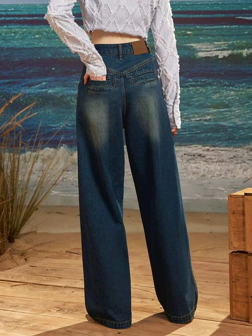 Back view of dark wash high rise retro wide leg jeans with vintage blue denim wash, curved back pockets and leather style waist label