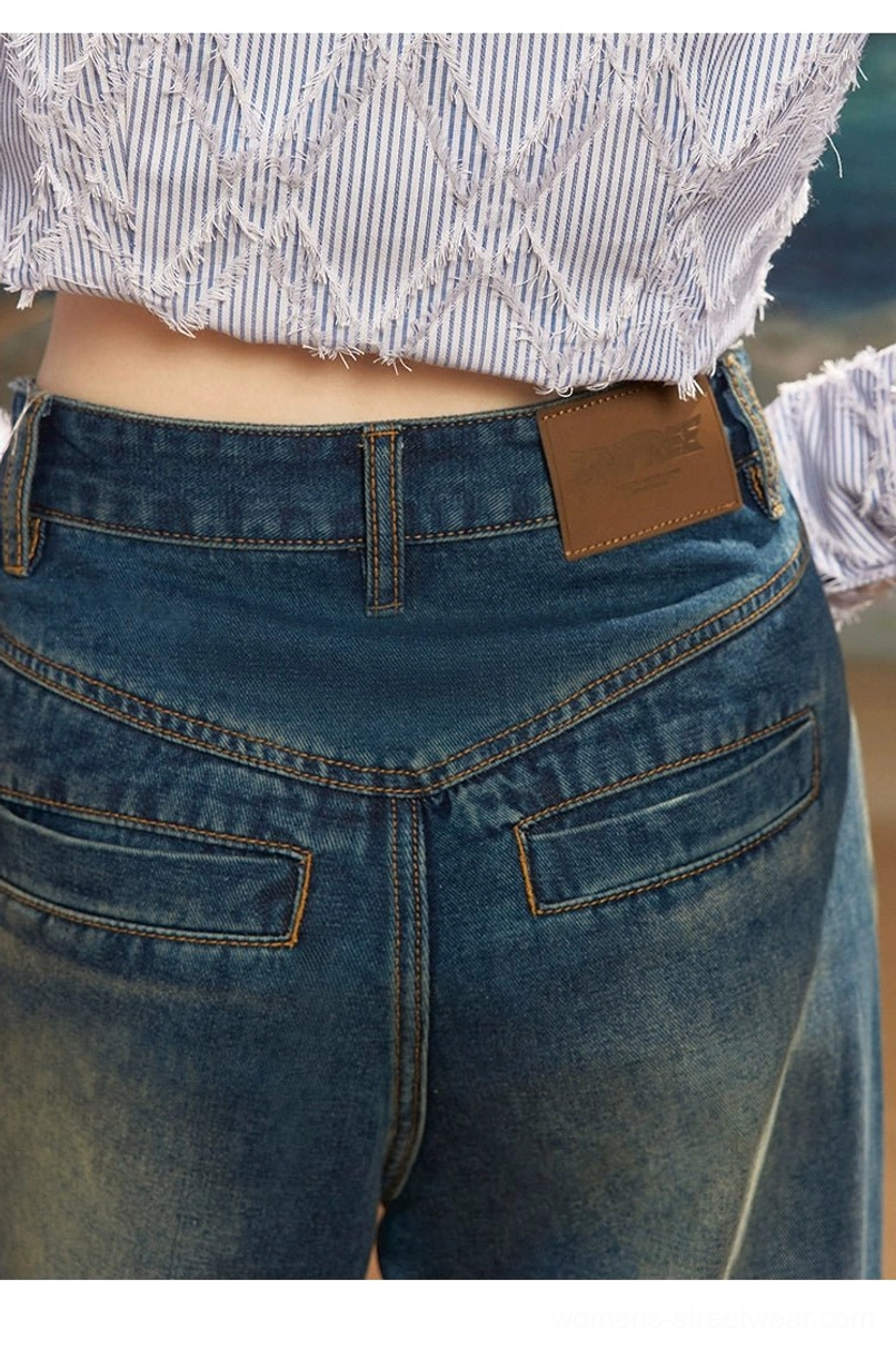 Close-up of dark wash retro wide leg jeans showing high waist, curved stitched back pockets and textured leather style label
