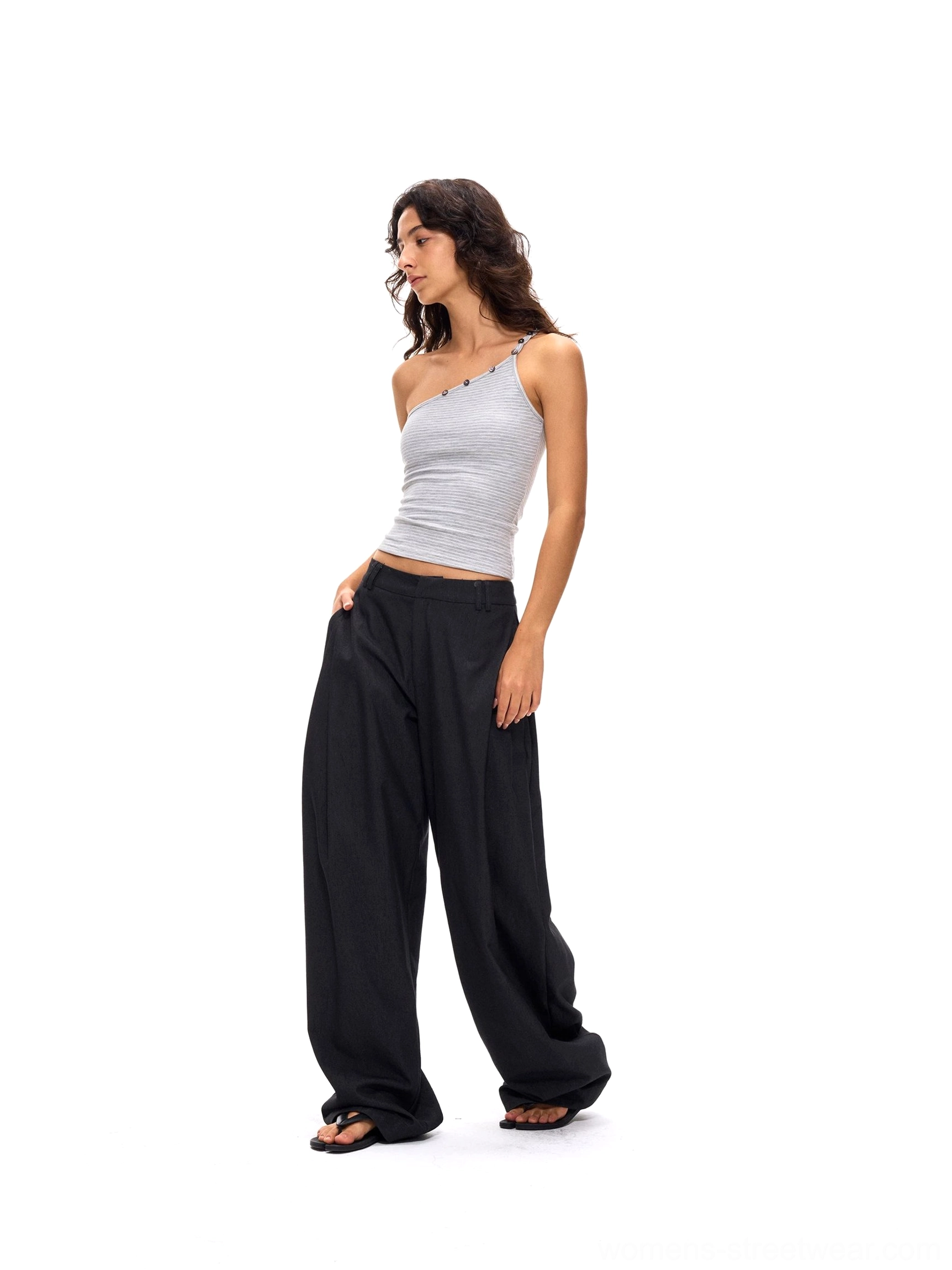 Deep gray pleated wide-leg streetwear suit pants shown from a left side full-body view with a relaxed tailored silhouette, soft front pleats, and open-toe sandals