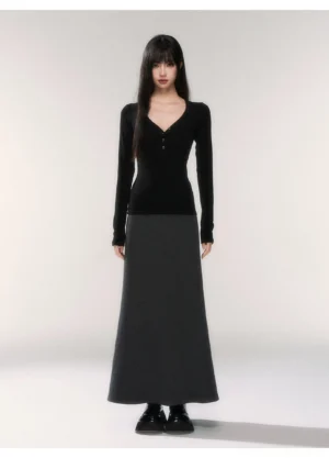 Black deep V-neck henley knit top with fitted long sleeves styled with a floor-length gray maxi skirt in a minimalist studio