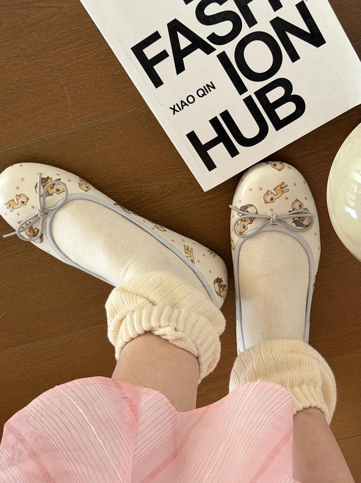 Deer puppy illustrated square-toe ballet flats with ribbon bow worn with a pink striped skirt in top-down detail view
