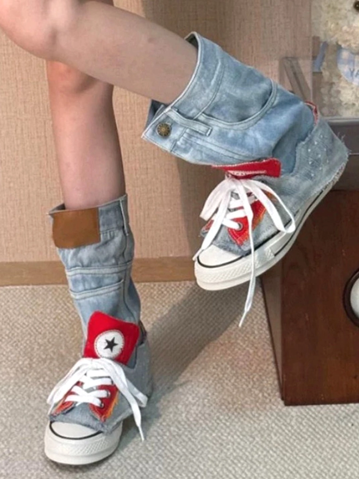 Dynamic on-foot view of denim fold-cuff platform sneakers showing one folded cuff, one raised cuff, white laces, and red star logos