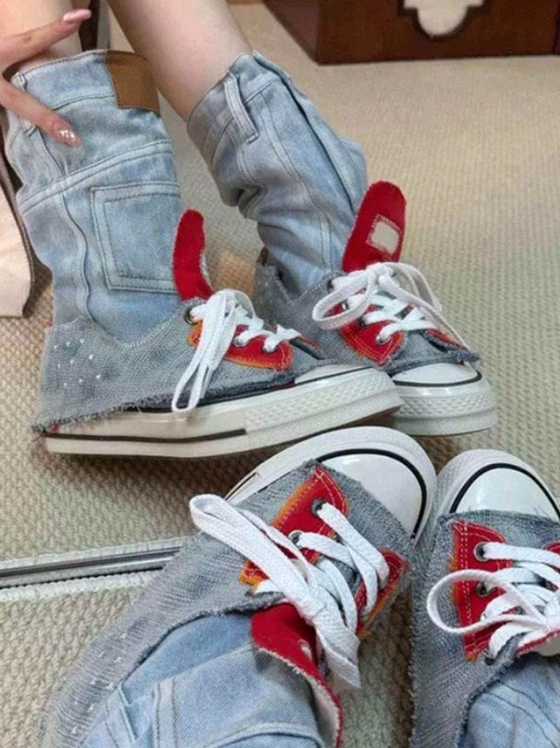 Close-up view of women's denim fold-cuff platform sneakers being adjusted, featuring pocket-inspired cuff details and light wash denim