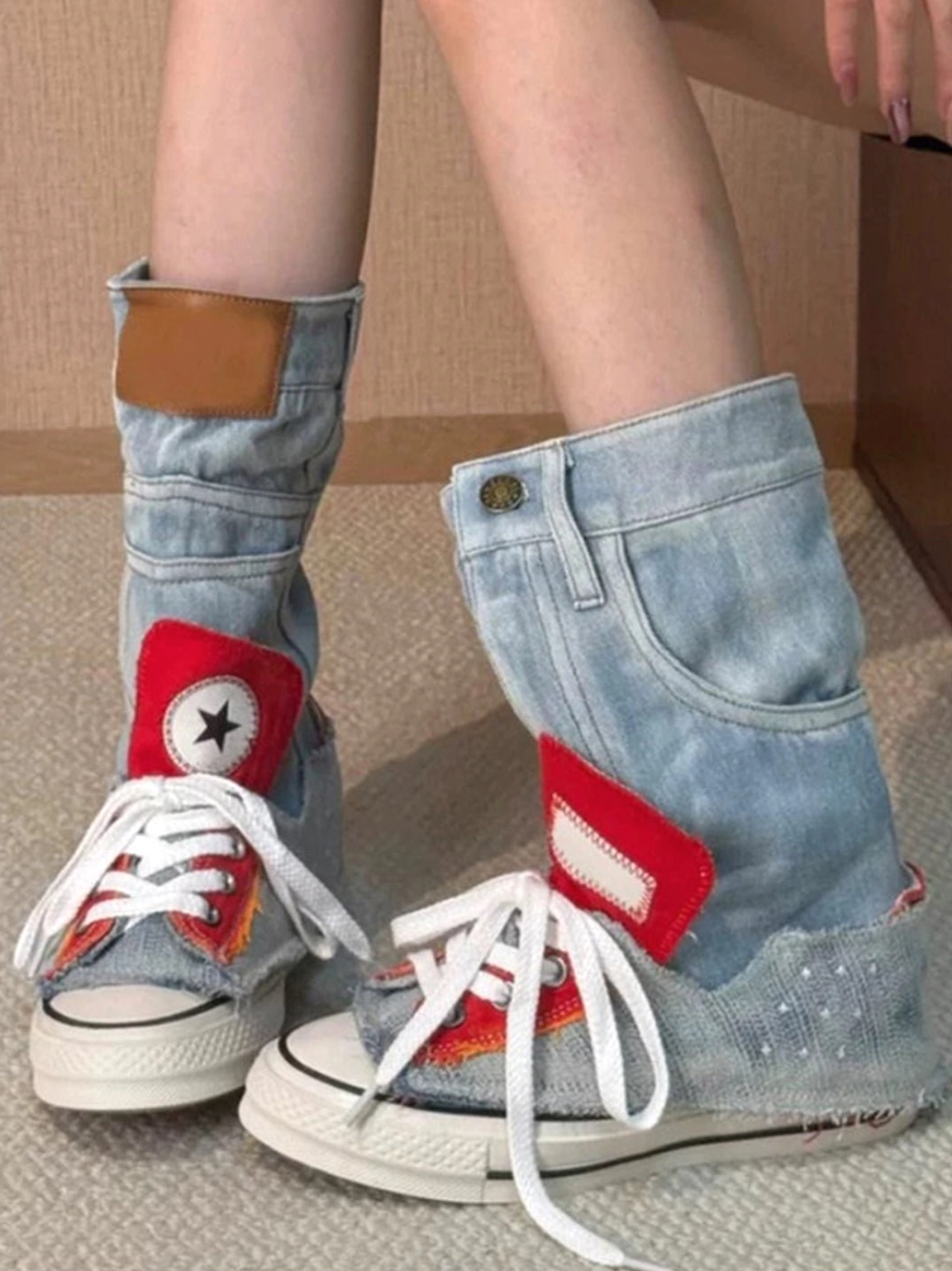 Side on-foot view of light blue denim high-top platform sneakers showing the foldable cuff and contrasting brown button tab