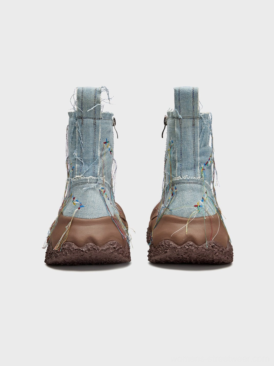 Rear three-quarter view of denim fringe western ankle boots with heel pull tabs and thick brown outsoles