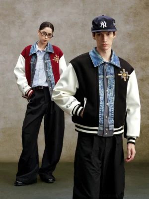 Denim panel embroidered varsity bomber jacket shown on two models in black and claret colorways with contrasting sleeves, denim-effect collar, chest embroidery, and striped ribbed trims