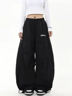 Black desert drift oversized parachute pants with extra wide legs and adjustable bungee ankle hems front view