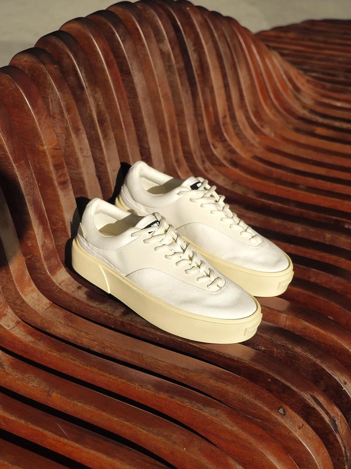 Pair of desert gray platform canvas sneakers displayed on an outdoor wooden bench, featuring neutral textile uppers and vintage cream rubber soles