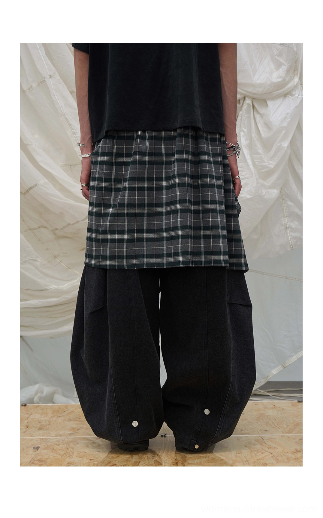 Back view of black detachable plaid layer balloon leg denim pants showing rounded wide-leg streetwear silhouette