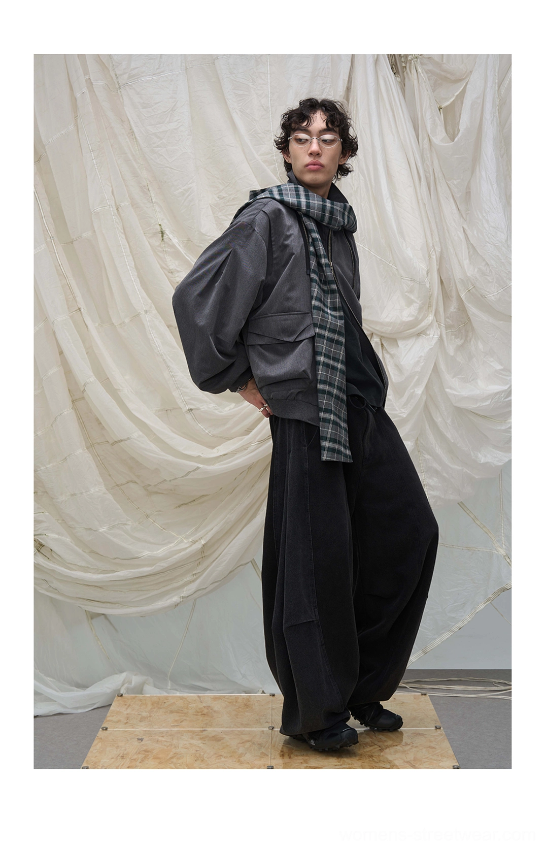 Black wide balloon leg denim pants with plaid layered waist styling and cropped gray jacket in studio