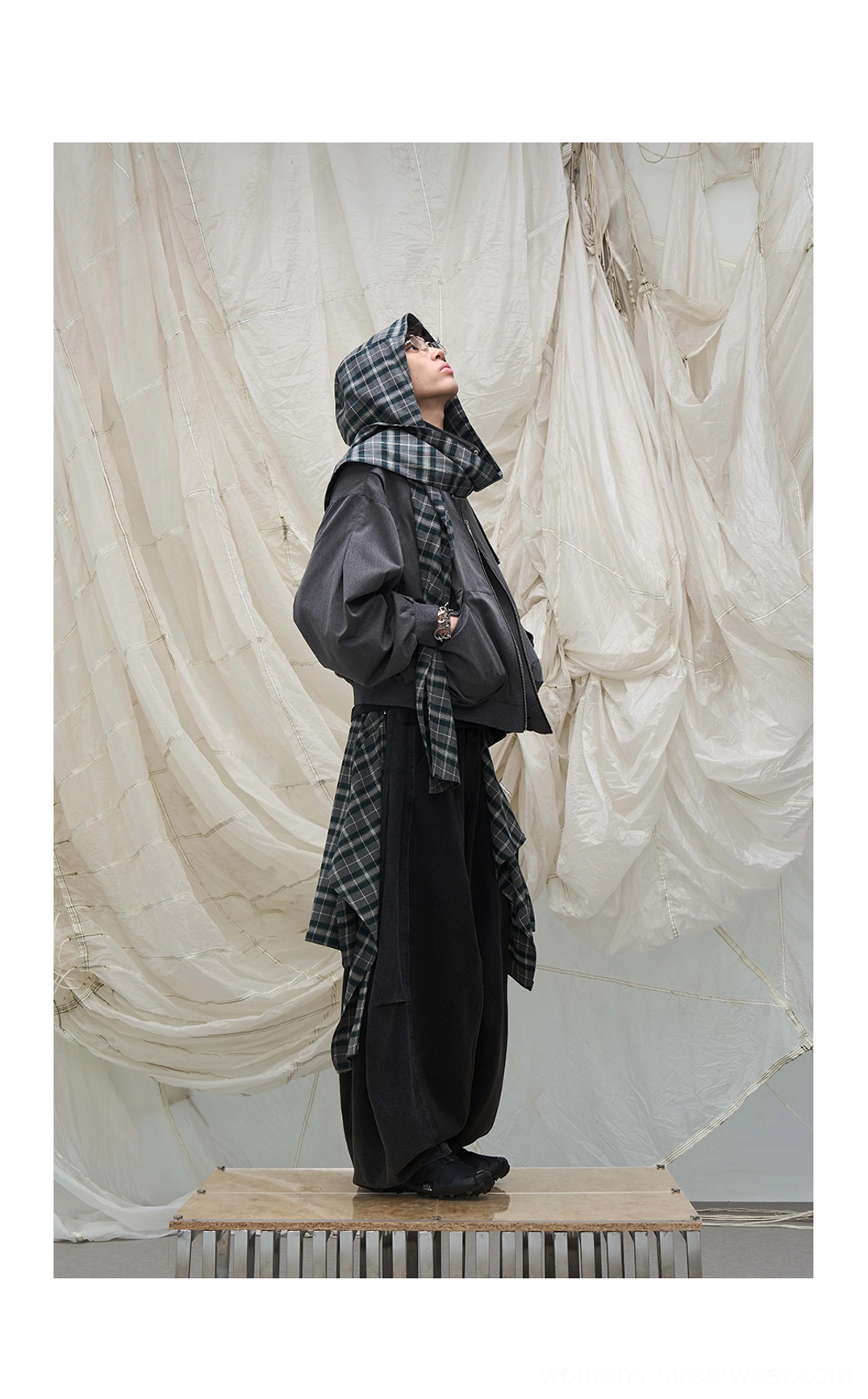Layered plaid balloon leg streetwear denim pants styled with a cropped hooded jacket and plaid shoulder accessory