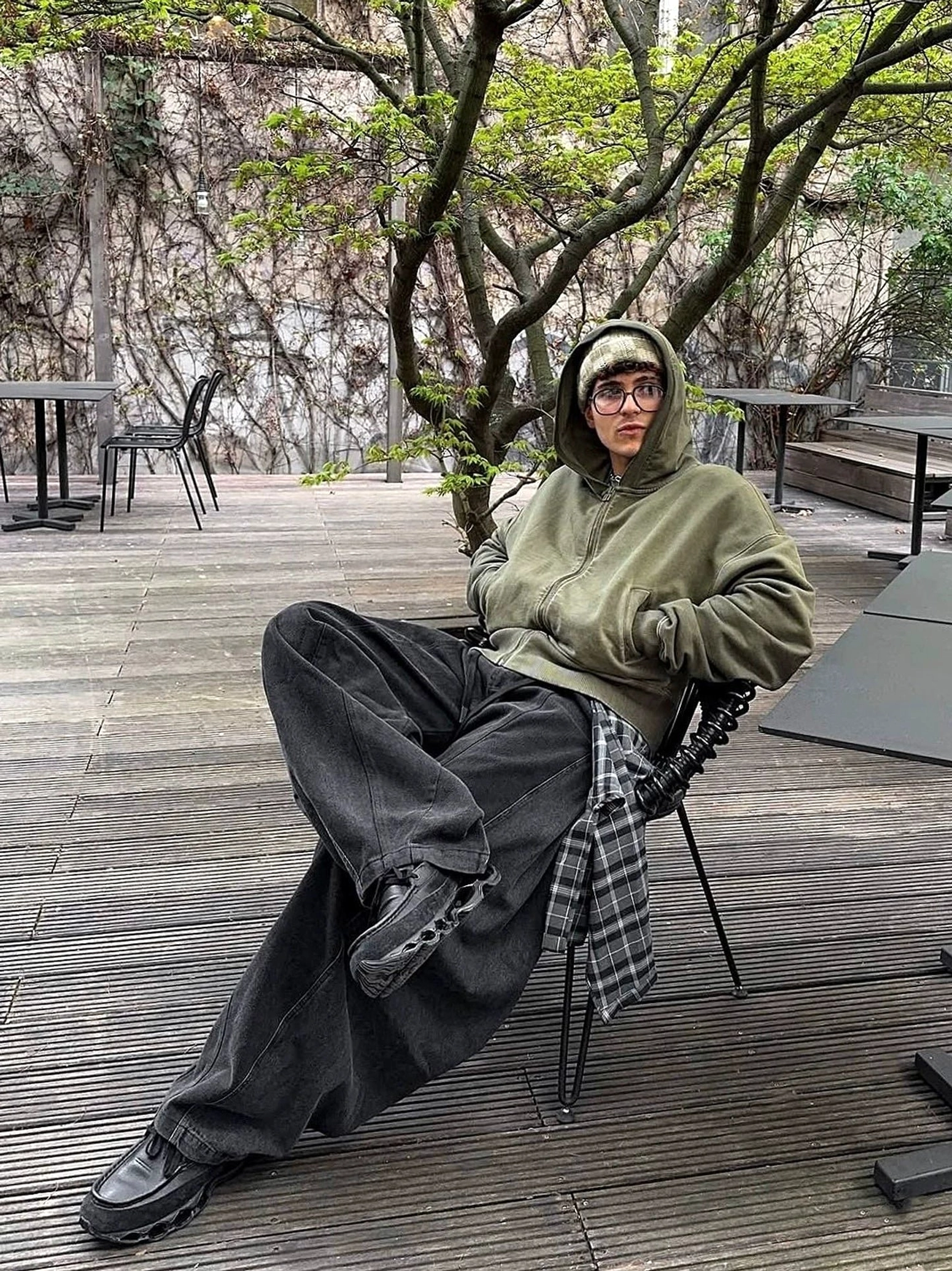 Relaxed black layered plaid balloon leg denim pants worn with an oversized olive hoodie in an outdoor streetwear outfit