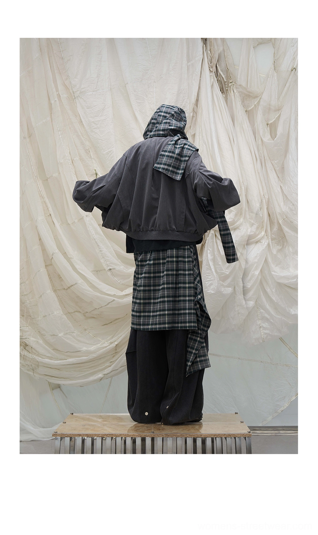 Rear view of oversized balloon leg denim pants with detachable plaid waist layer and cropped hooded outerwear